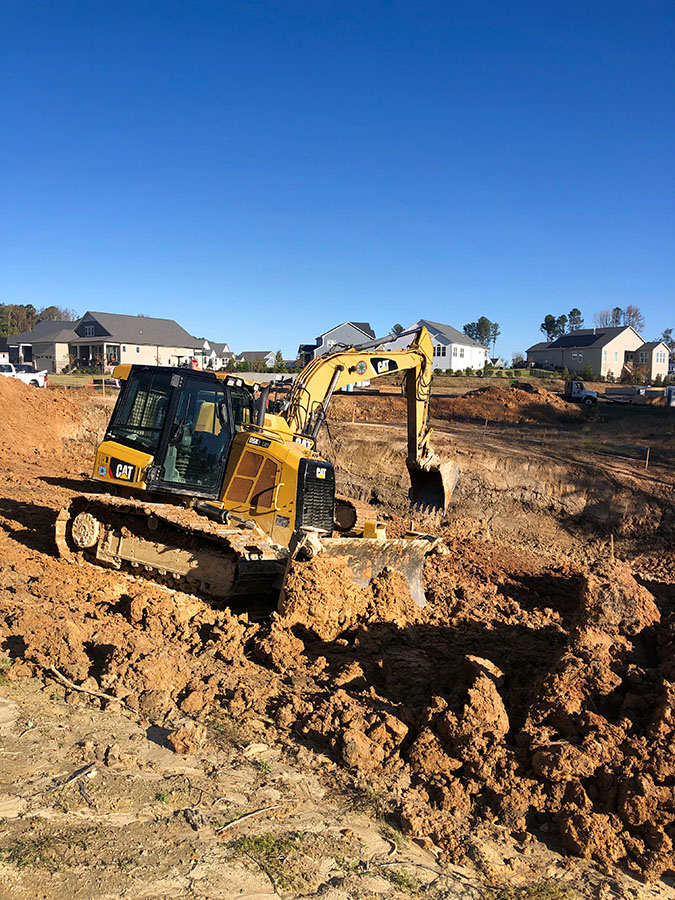 A hydraulic excavator and a bulldozer excavate a site in the beginning stages of a lot remediation project.