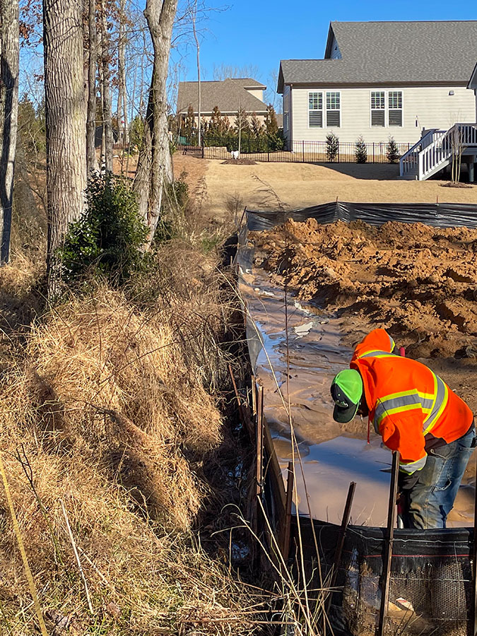 Silt fencing installed to protect land from runoff during a pond remediation project.